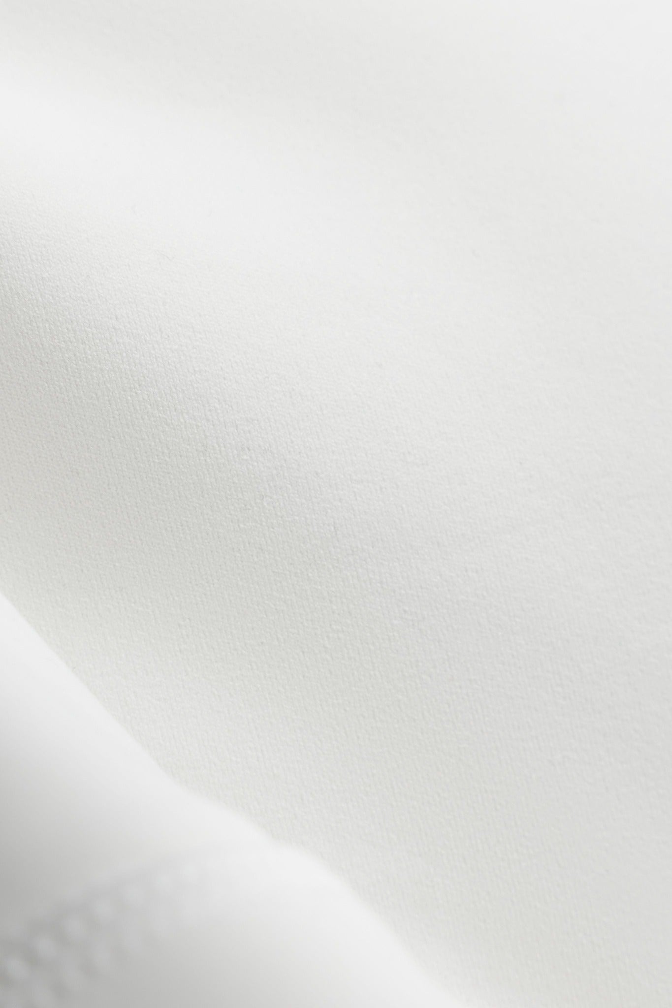 Close-up of the smooth matte white Cloudform fabric on a CASPARA sports bra.